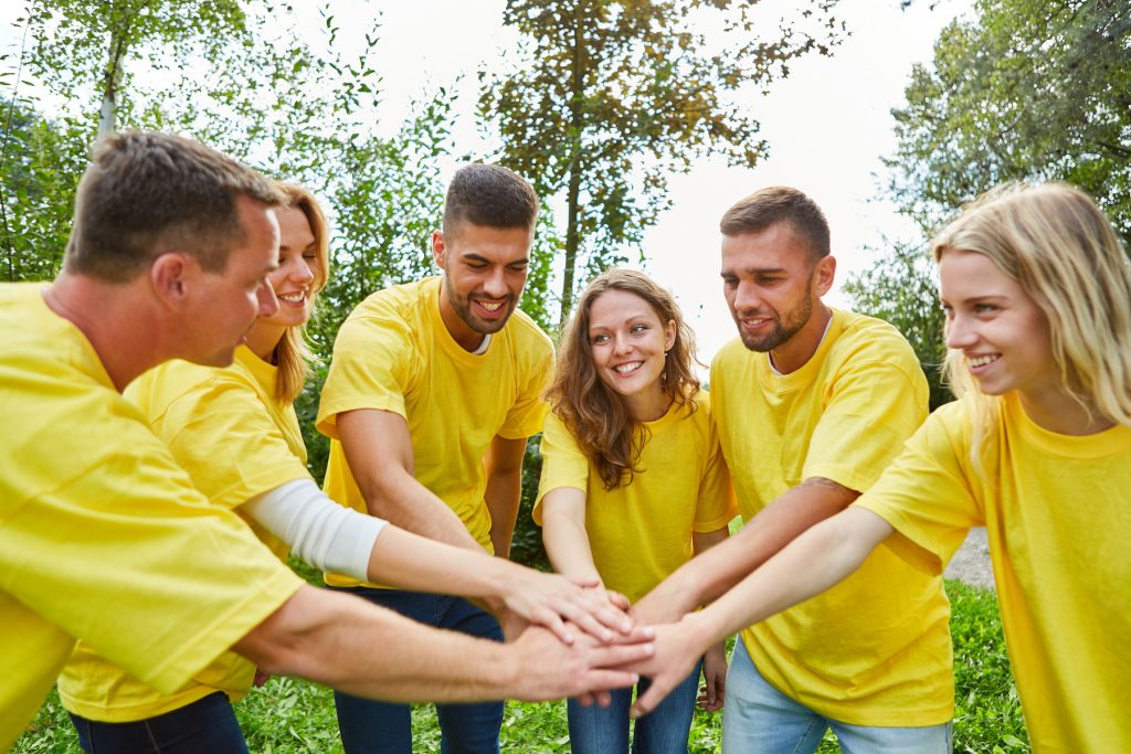 Young people in the start-up team pile up hands for motivation and teambuilding