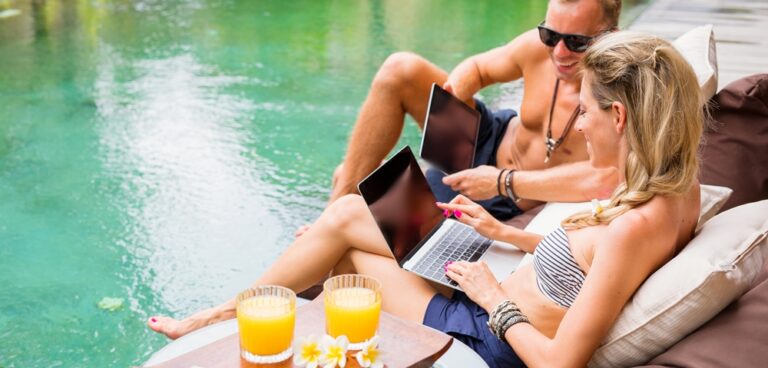 Young people working by the pool, during business travel