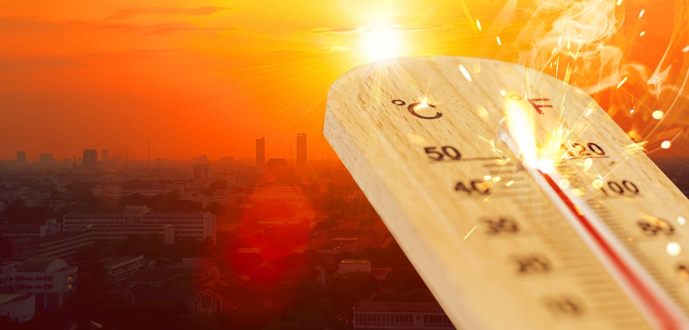 Is It Too Hot to Work? High Temperatures and the Workplace summer hot weather season high temperature thermometer with city view.