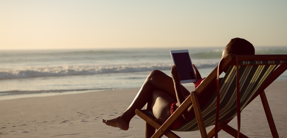The £5,000 cabin bag: Why travellers are carrying more value than ever before Reading an ipad on the beach